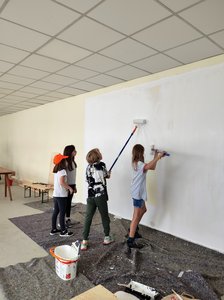 Bild von der Bauwoche: Kinder streichen eine Wand weiß an.