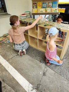 Bild von der Bauwoche: Kinder bekleben ein Holzregal mit Schnipseln aus Disney-Comics.