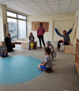Bild von der Bauwoche: Kinder, Eltern, Mitarbeiterinnen sitzen im neuen Raum auf dem Boden und auf selbstgebauten Podesten.