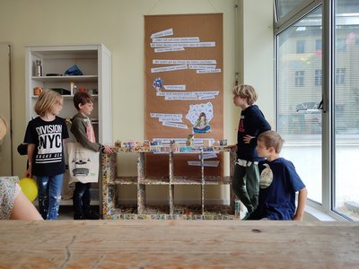 Bild von der Bauwoche: Kinder präsentieren als Gruppe das mit Comics beklebte Regal.