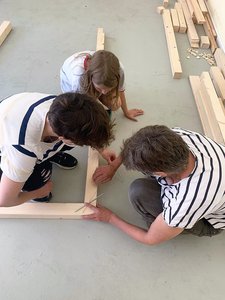 Bild von der Bauwoche: Kinder messen Teile eines Holzgestells.