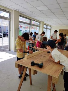Bild von der Bauwoche: Kinder arbeiten zusammen mit verschiedenen Werkzeugen an den Möbeln.